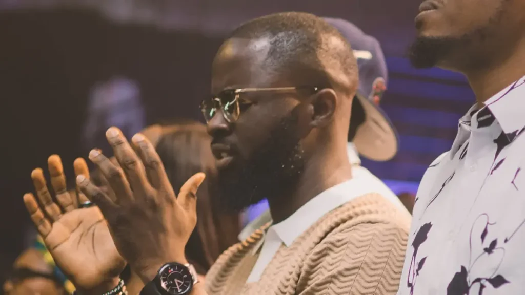 How to Pray: A man lifting his hands and praying to God during Harvesters' church service.